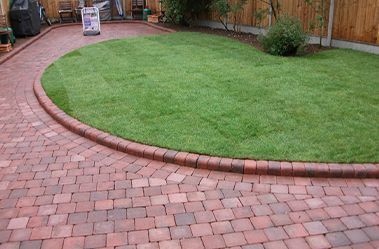 A brick walkway leading to a lush green lawn.