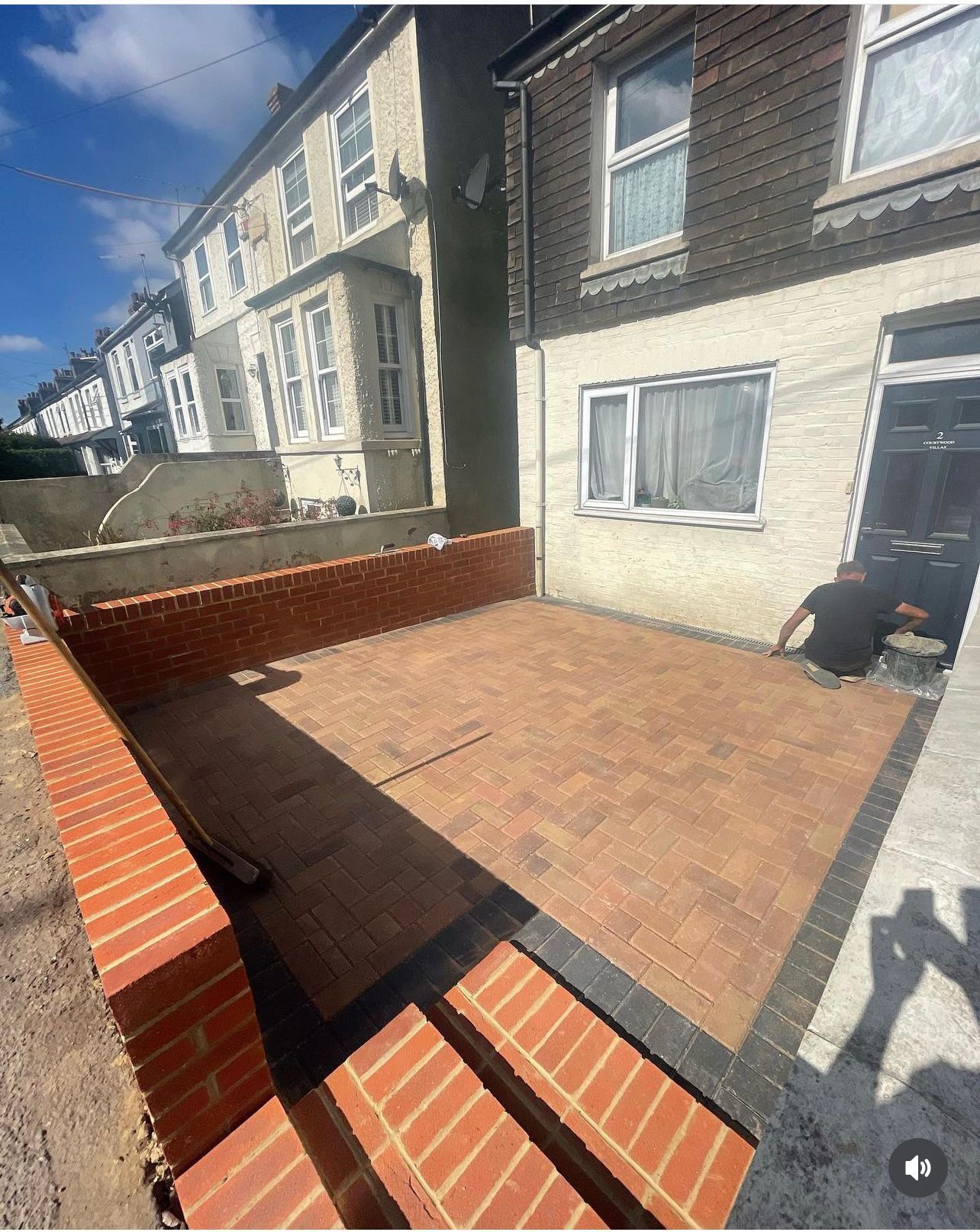 A man is working on a patio in front of a house.