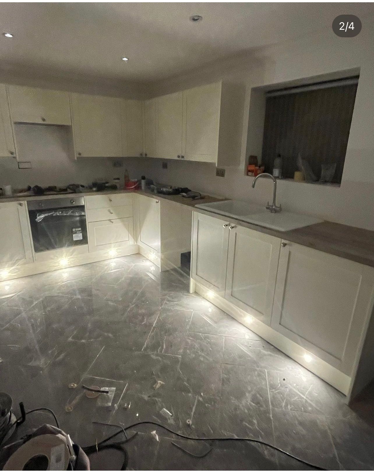 A kitchen with white cabinets , a sink , and a stove.