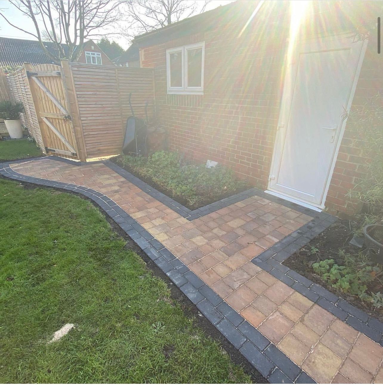 A brick walkway leading to a brick building in a backyard.