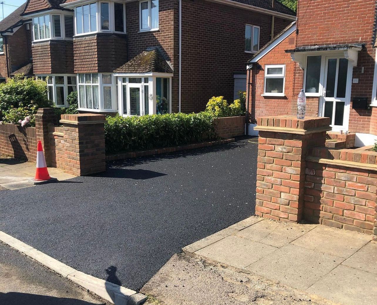 A brick house with a black driveway in front of it.