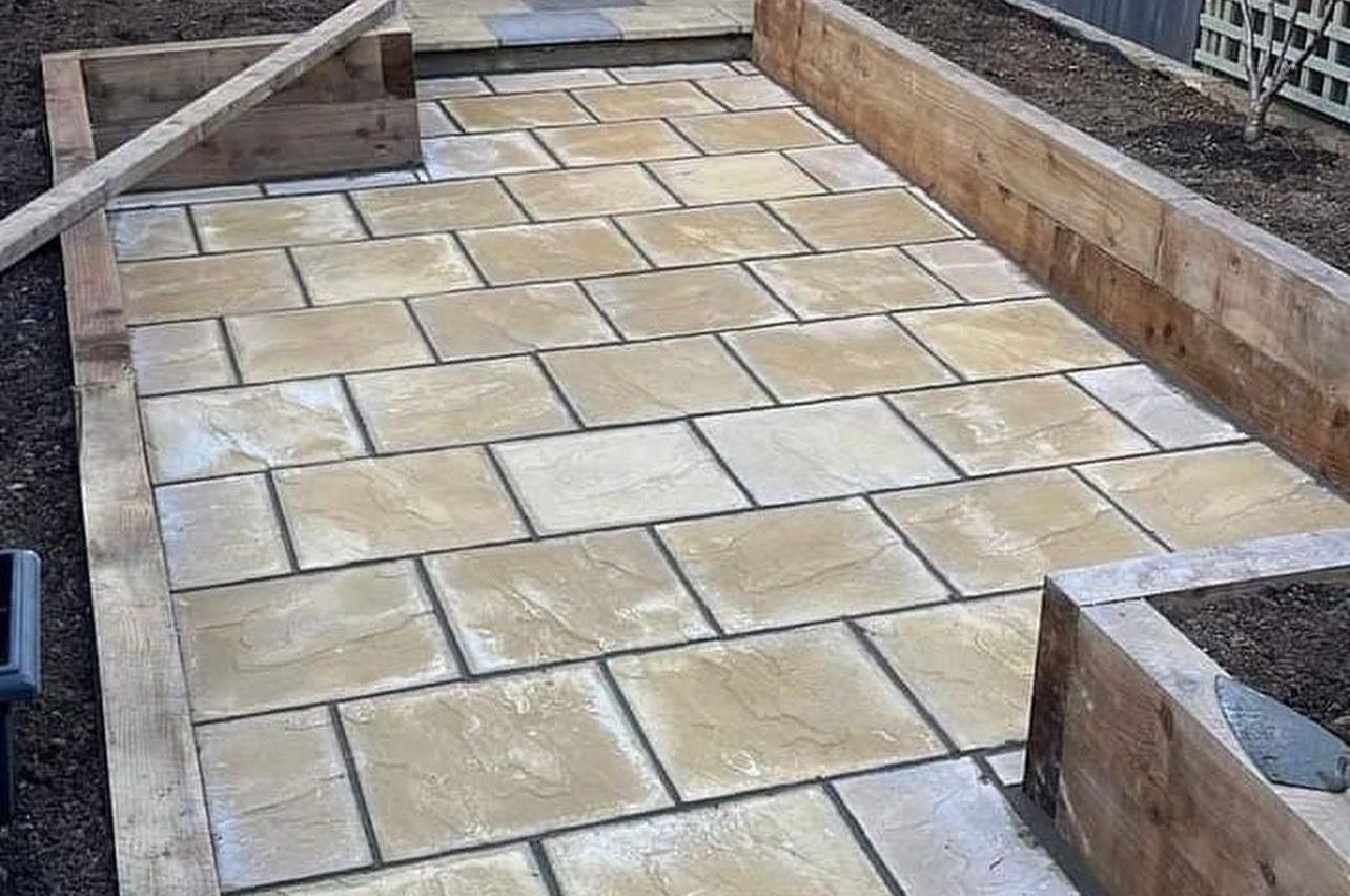 A brick walkway surrounded by wooden planters in a garden.