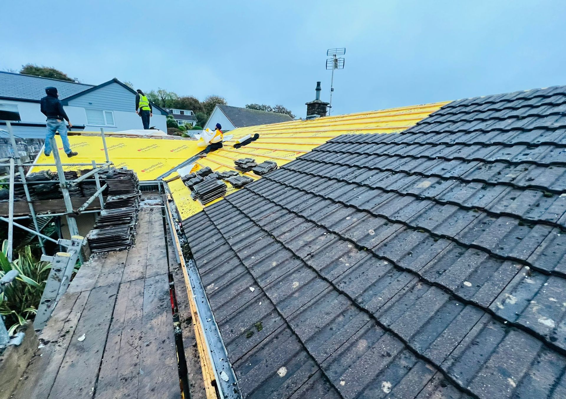 A man is standing on a scaffolding on top of a roof.