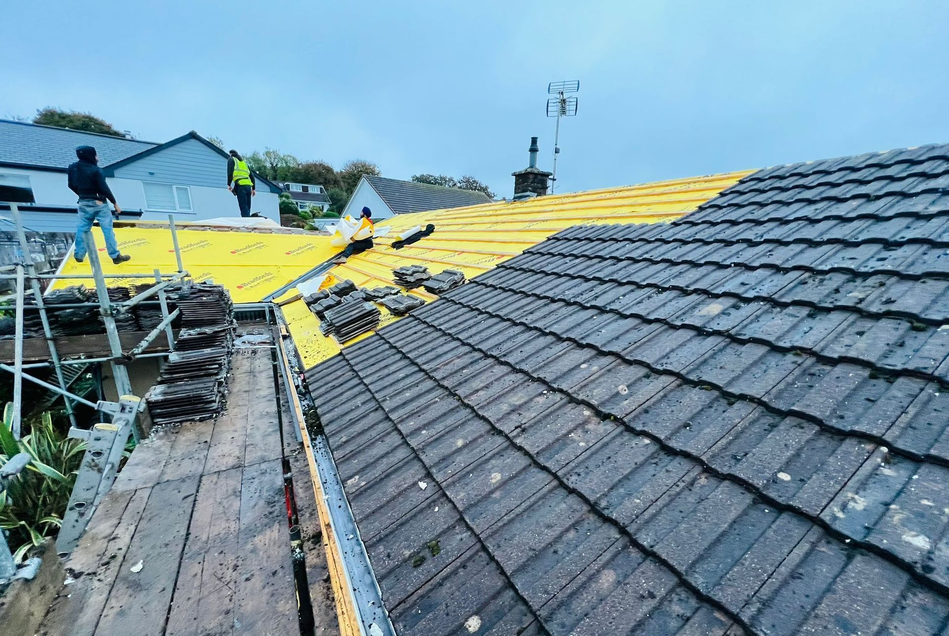 A man is standing on a scaffolding on top of a roof.