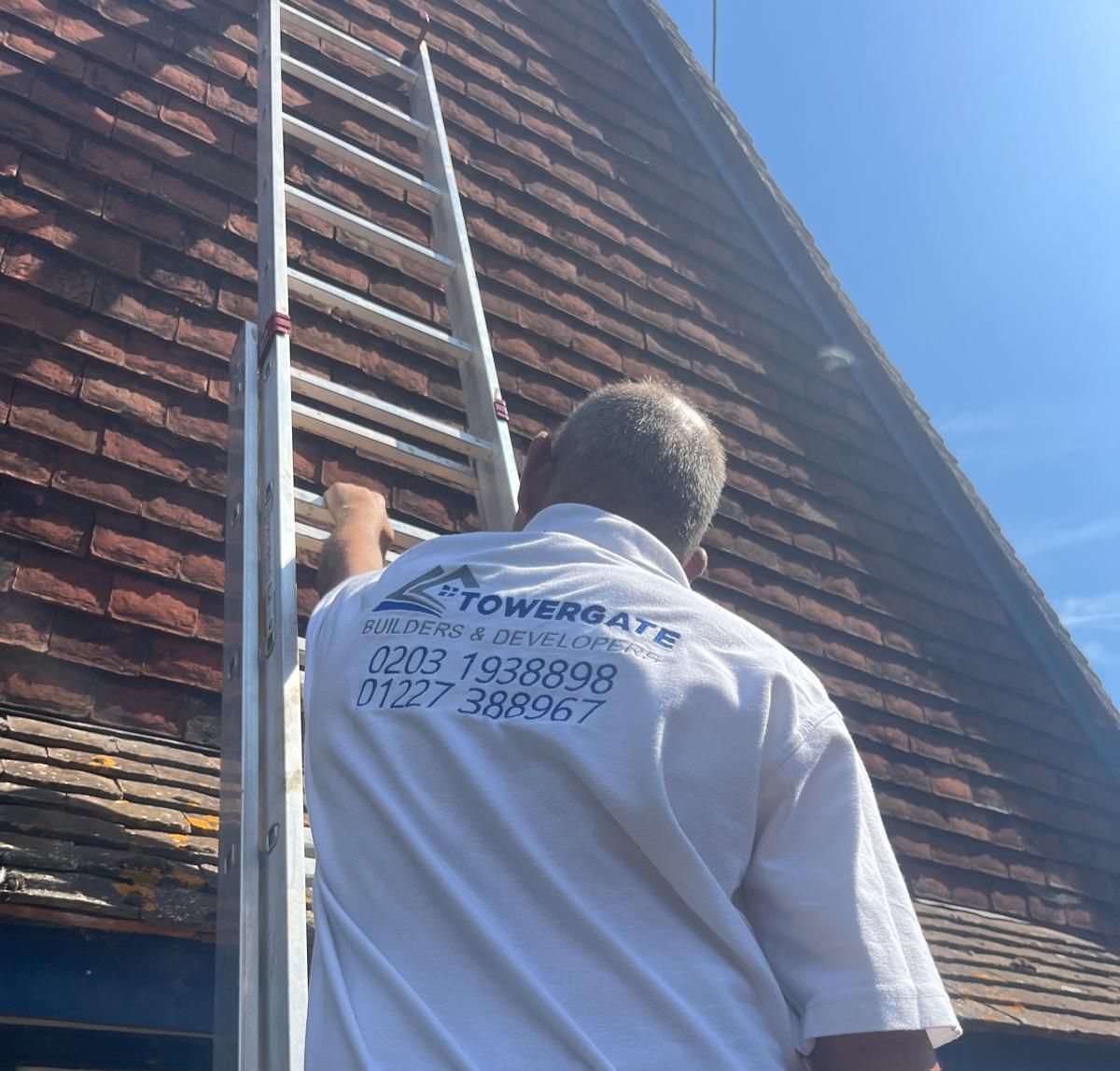 A man is standing on a ladder on the side of a building.