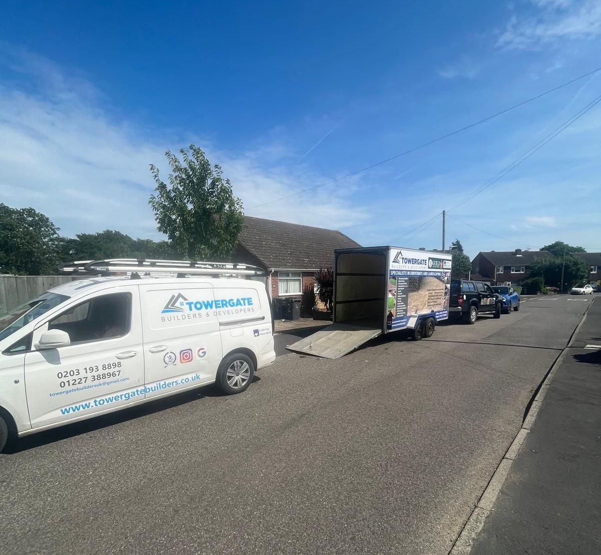 A white van is parked on the side of the road next to a trailer.