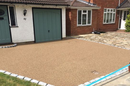 A driveway in front of a house with a green garage door.