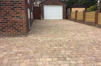 A brick driveway leading to a garage with a white garage door.