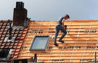 A man is working on the roof of a house.