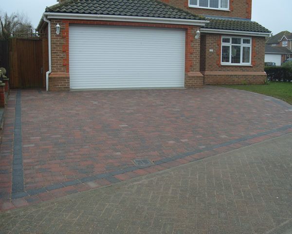 A brick house with a white garage door and a brick driveway