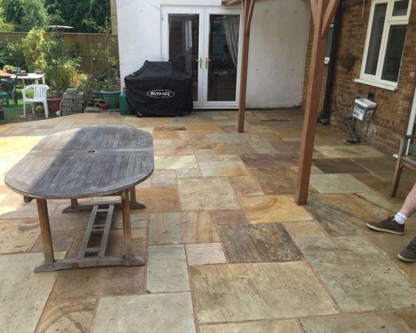 A person is standing on a patio with a table and chairs.