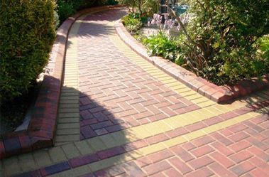 A brick walkway surrounded by trees and bushes in a garden.