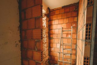 A room with a brick wall and a ladder in it.