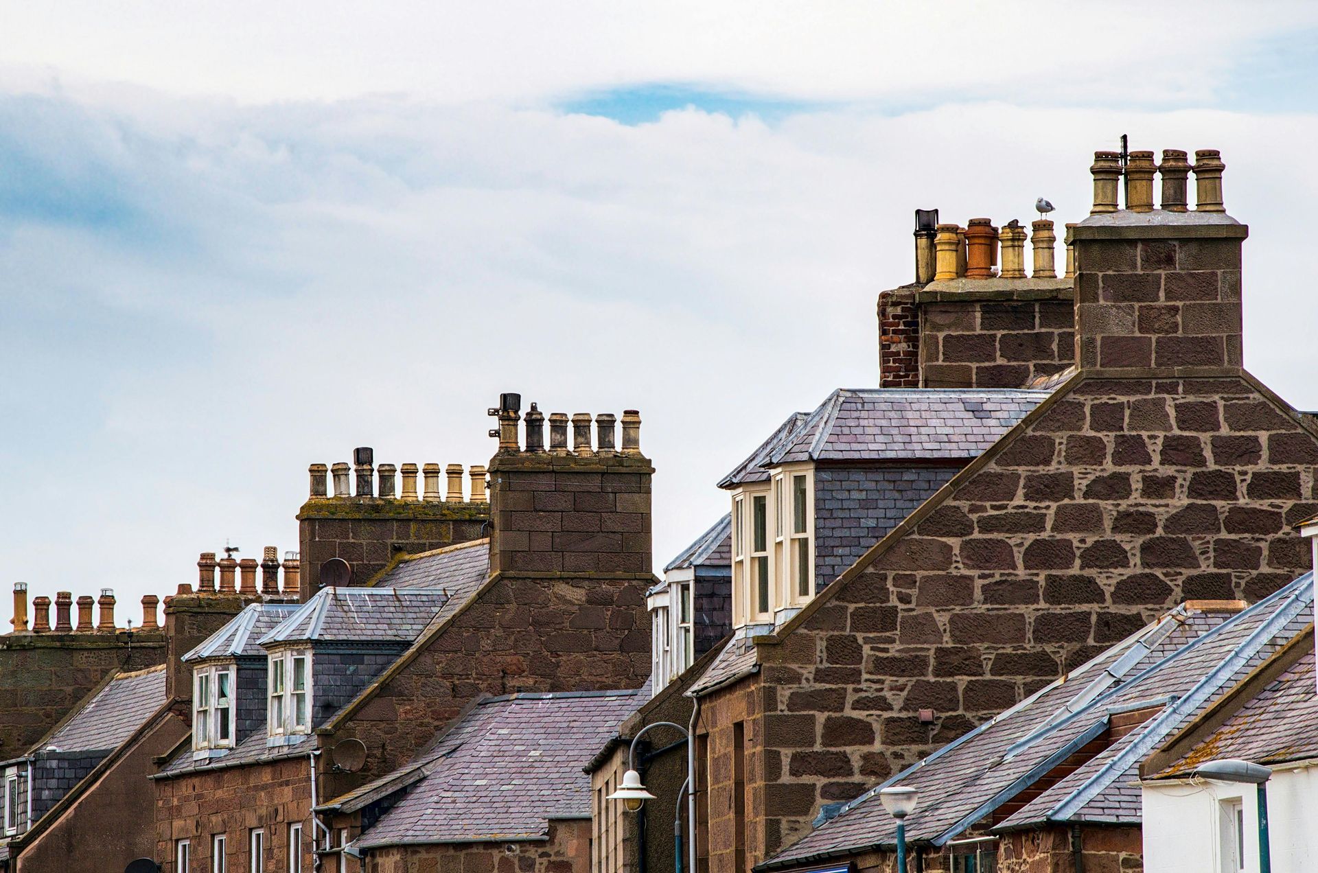 A row of brick houses with chimneys on the roofs.