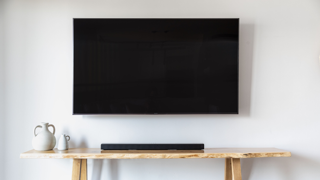 A flat screen tv is mounted on a wall above a wooden table.