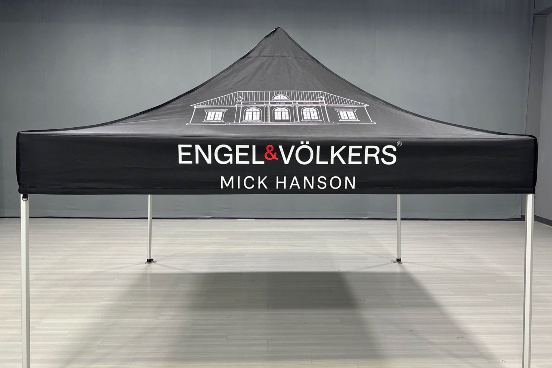 Black Engel & Völkers Mick Hanson pop-up tent in an empty indoor space