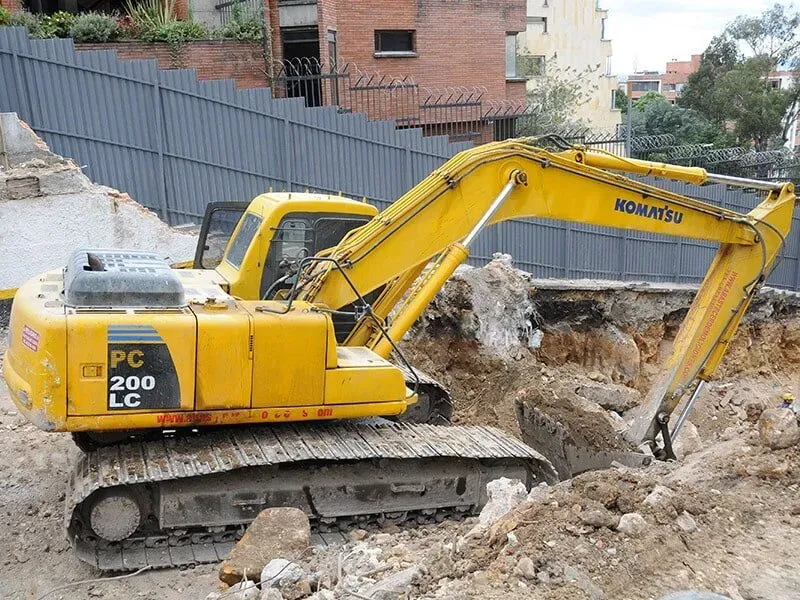 Una excavadora Komatsu amarilla está cavando un hoyo en la tierra.