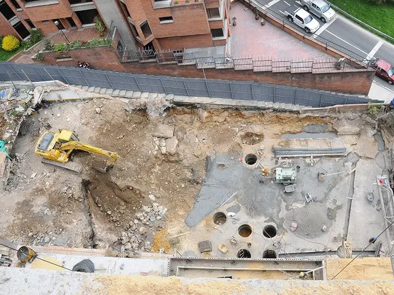 Una vista aérea de un sitio de construcción con una excavadora amarilla.