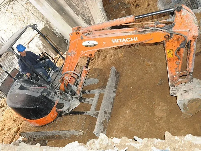 Una excavadora Hitachi está cavando un hoyo en el suelo.