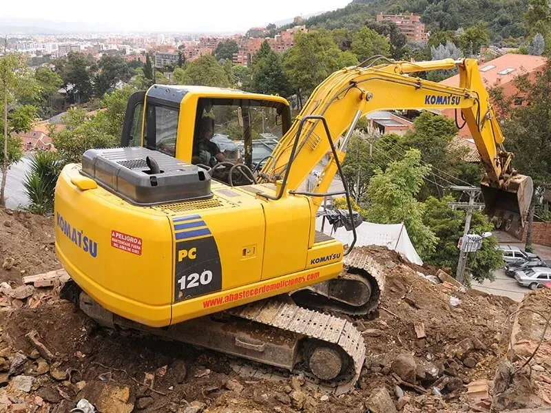 Una excavadora amarilla está sentada encima de un montón de tierra.