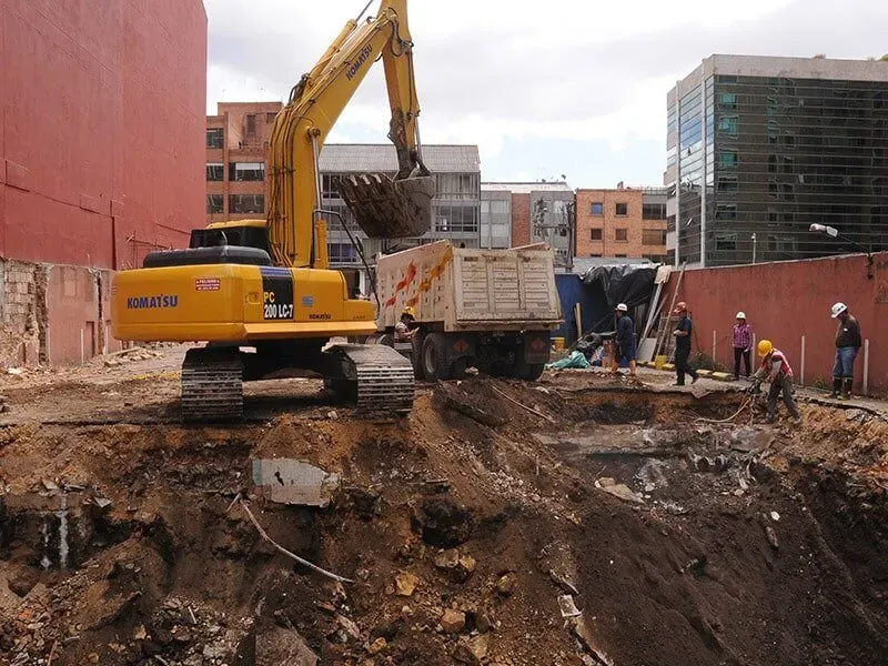 Una excavadora Komatsu amarilla está cargando tierra en un camión volquete.