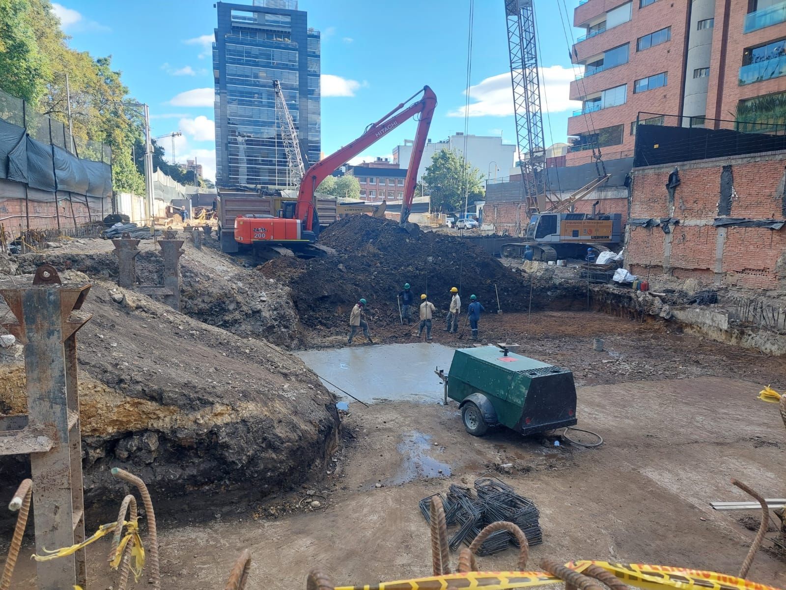 Una obra en construcción con mucha tierra y un edificio al fondo.