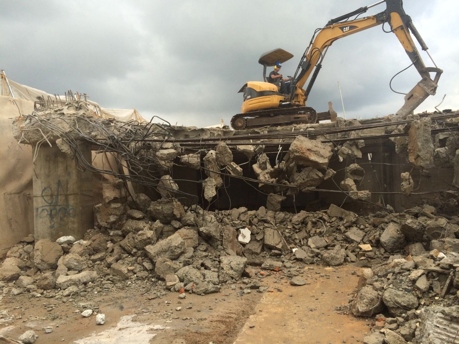 Una excavadora amarilla está demoliendo una estructura de hormigón.
