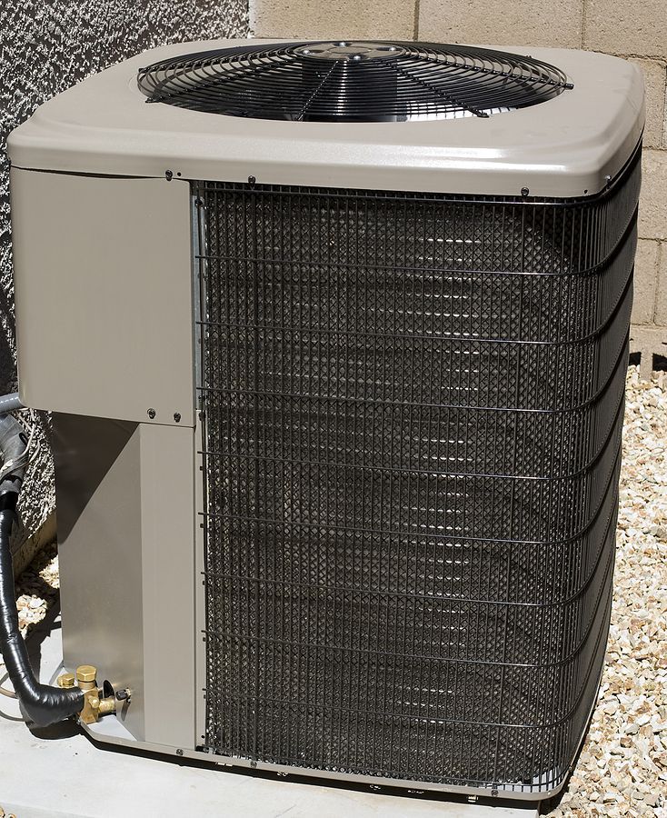 An outdoor air conditioning unit with metal fins, fan, and beige casing.