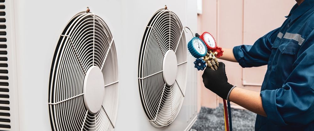 HVAC technician servicing an air conditioning unit, connecting gauges.