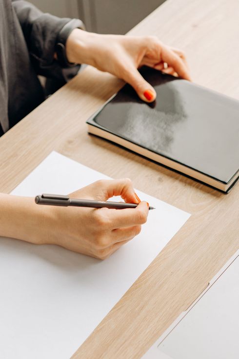 A woman is writing on a piece of paper with a pen.