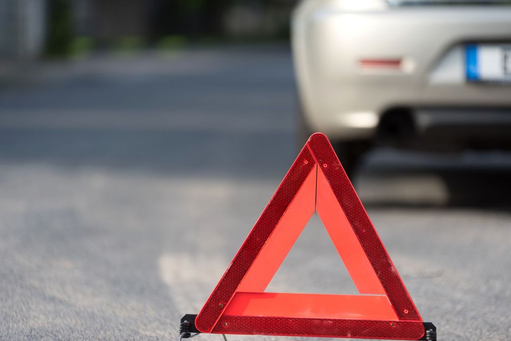 Un triangolo rosso è posizionato sul ciglio della strada davanti a un'auto.