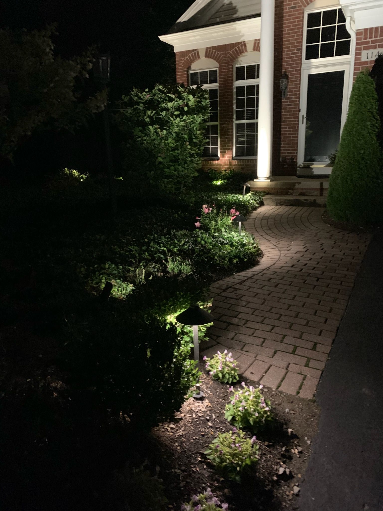 A brick walkway leading to a house at night