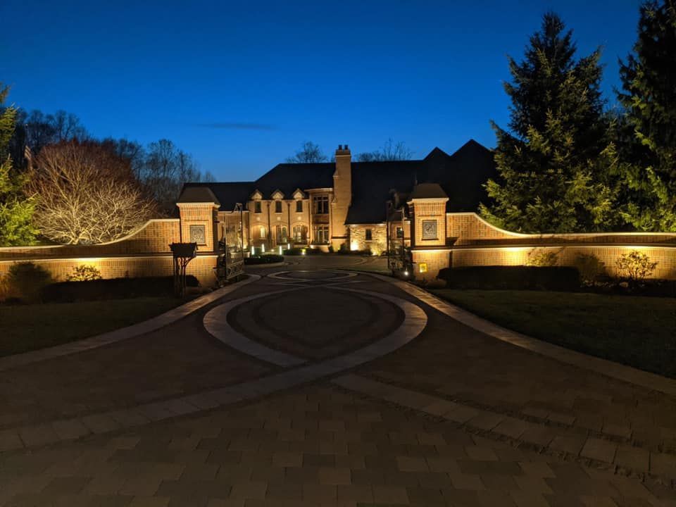 A large house with a driveway leading to it is lit up at night