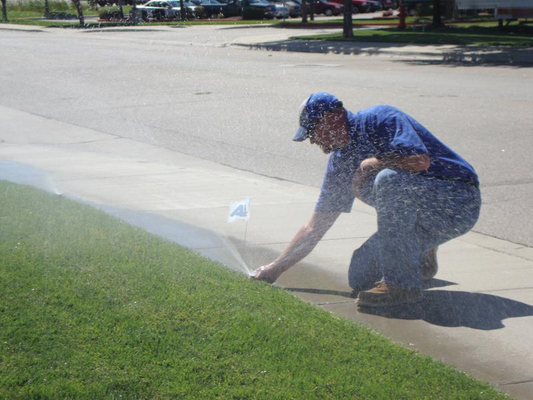 A man is watering a lawn with a hose.