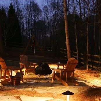 A patio with chairs and a fire pit at night