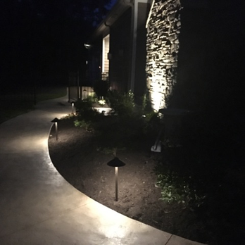 A walkway is lit up at night in front of a house