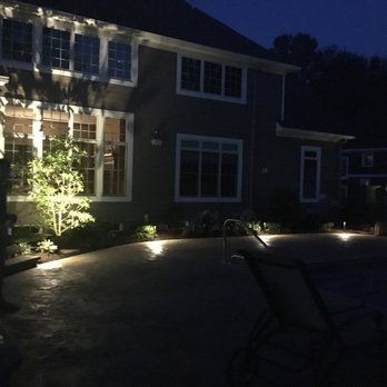 A house is lit up at night with a pool in front of it