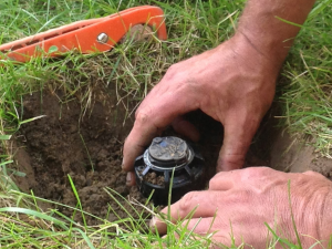 A person is digging a hole in the ground to install a sprinkler