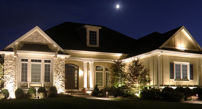 A large house is lit up at night with the moon in the background