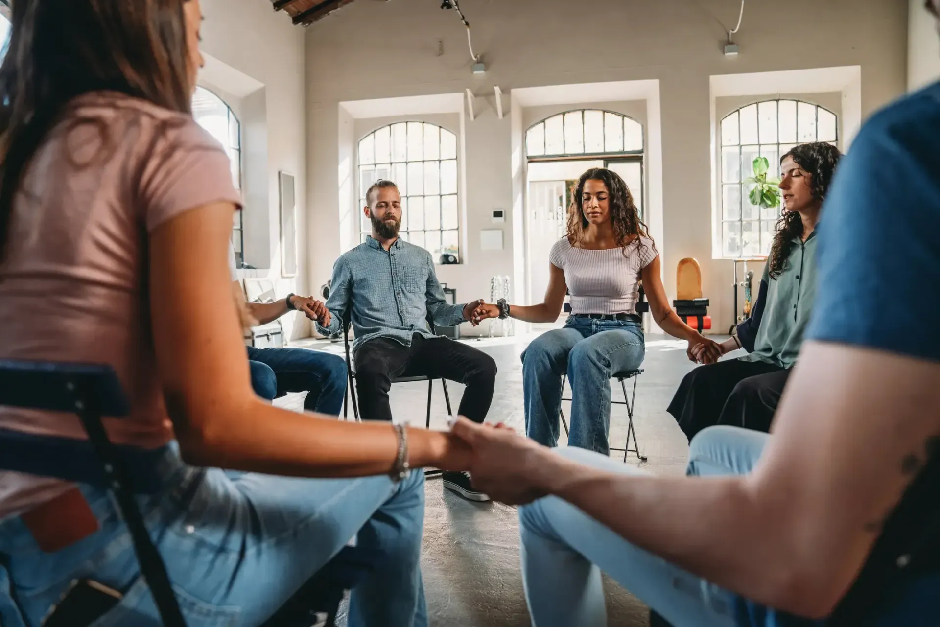 Woman with dark hair smiles, wearing a blue top, against a white background.