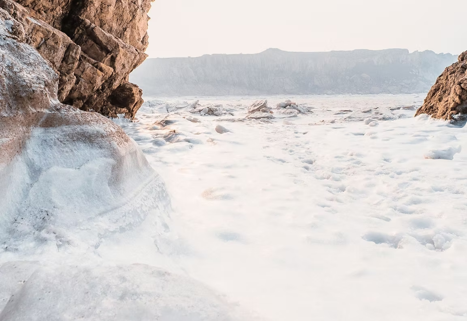 Rocks framing a snowy landscape, overlooking a hazy, snowy horizon.