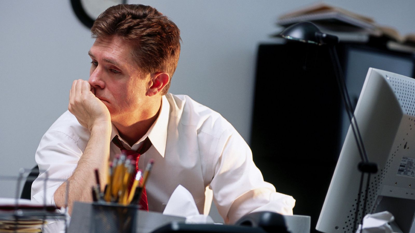 Woman with dark hair smiles, wearing a blue top, against a white background.
