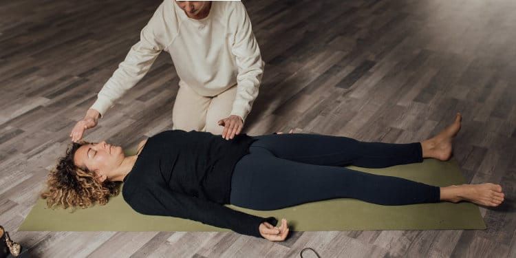 Woman with dark hair smiles, wearing a blue top, against a white background.