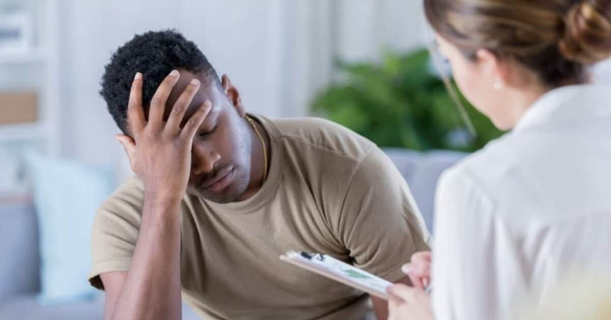 Woman with dark hair smiles, wearing a blue top, against a white background.
