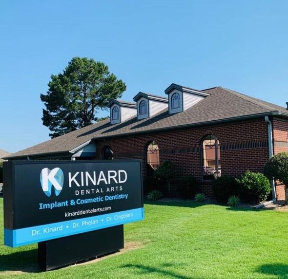 a sign for kinard dental arts in front of a brick building