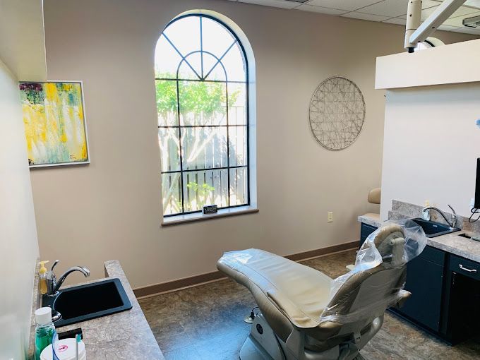 a dental office with a dental chair , sink , and window .