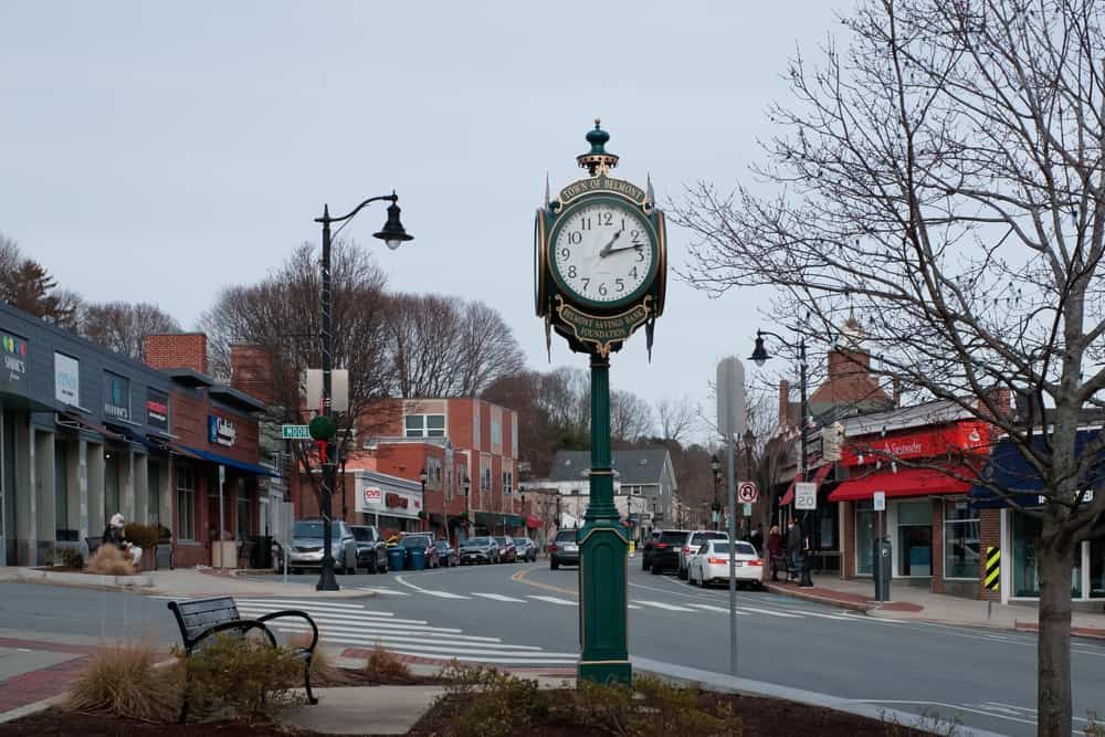 A clock on a pole in the middle of a city street.