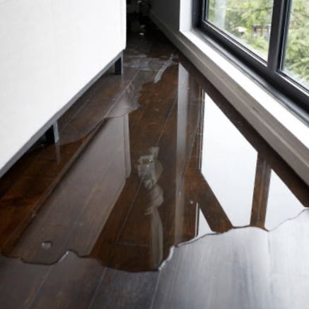 A puddle of water on a wooden floor next to a window