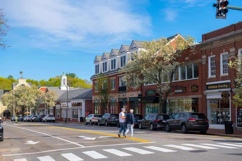 A couple of people are crossing the street in a small town.