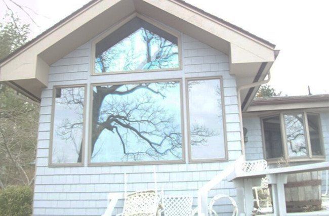 A house with a large window and a tree reflected in it